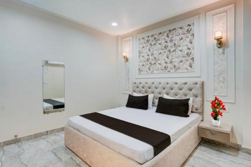 a white bedroom with a large bed and a mirror at Super Townhouse DSIDC Bawana Formerly Kanhaiya Residency in Delhi
