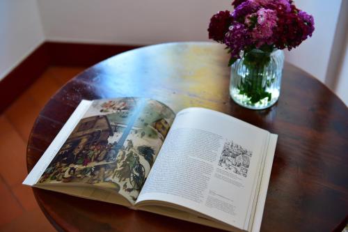 an open book on a table with a vase of flowers at Pousada Convento de Beja in Beja