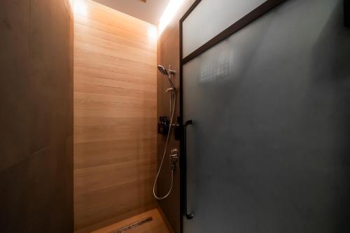 a door to a shower in a bathroom with wooden walls at Sleepover Terminal 3, Concourse B - formerly sleep 'n fly in Dubai