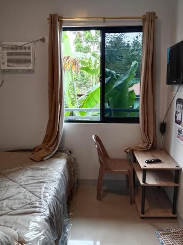 a bedroom with a window and a chair and a table at RMBC beds and breakfast in Badian