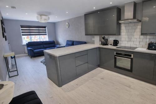 a kitchen with gray cabinets and a living room at Liverpool House Near City Centre in Liverpool