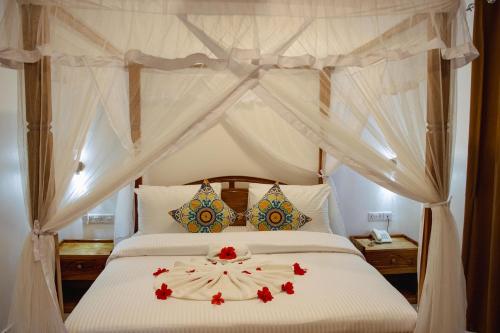 a bedroom with a canopy bed with red flowers on it at Shangani Hotel in Zanzibar City