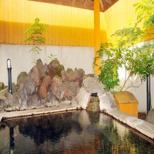 a pool of water in a garden with a rock wall at Yumoto Ginsenkaku in Kamikawa