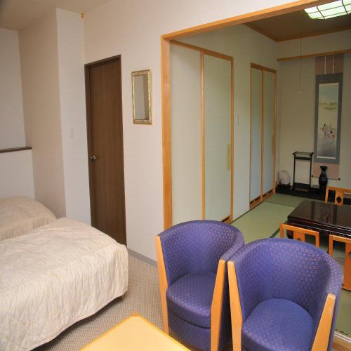 a room with two chairs and a bed and a table at Yumoto Ginsenkaku in Kamikawa
