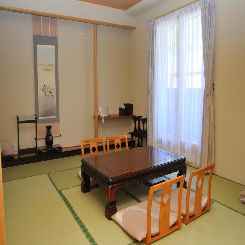 a dining room with a wooden table and chairs at Yumoto Ginsenkaku in Kamikawa