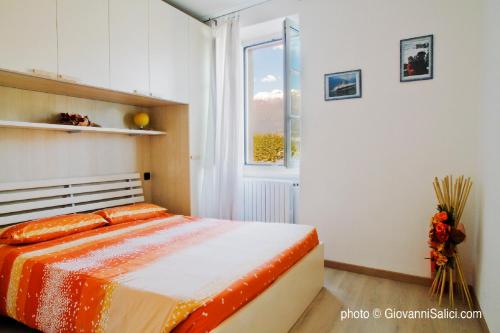 een slaapkamer met een bed met een oranje dekbed en een raam bij Bella Piazza in Colico