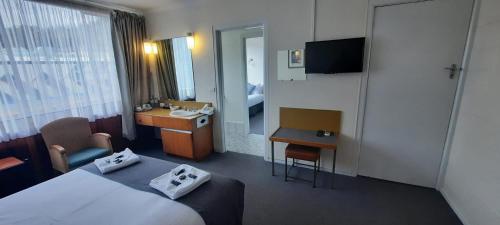a hotel room with a bed and a sink at Mt Lyell Motor Inn - By Orangepete in Queenstown