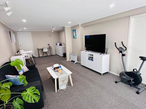 a living room with a couch and a flat screen tv at Large 1BR Suite and Private Lounge in Tauranga