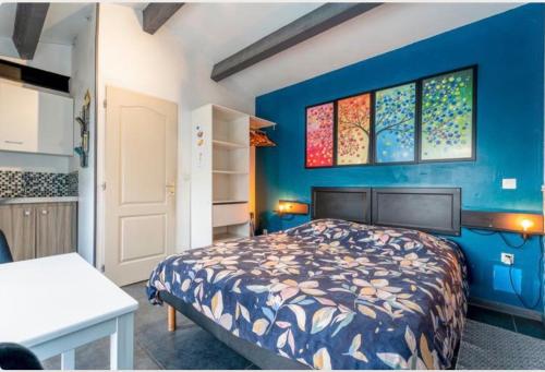 a bedroom with a bed and a blue wall at Chez Frédérique et Jean-Claude in Les Taillades