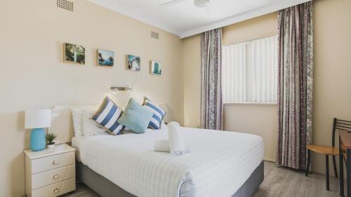 a bedroom with a white bed and a window at Priority Beach Stay in Coffs Harbour