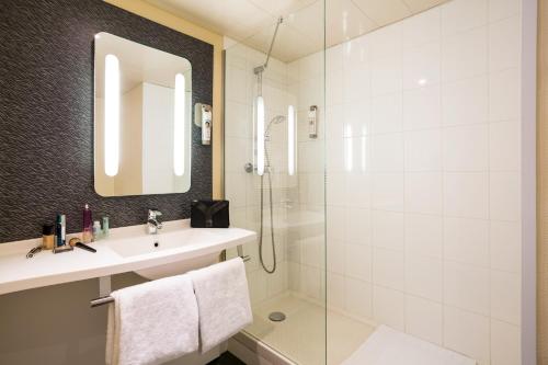 La salle de bains est pourvue d'un lavabo et d'une douche. dans l'établissement ibis Bordeaux Lac, à Bordeaux