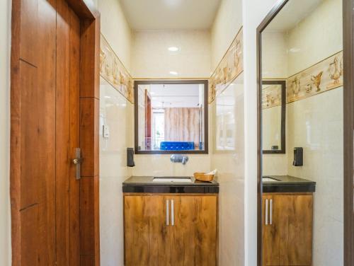 a bathroom with a sink and a wooden door at Tripli Hotels Shivaay in Dharamshala