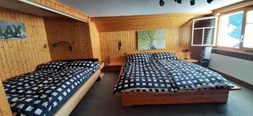 two beds in a bedroom with wooden walls at Ferienwohnung Toggilodge in Unterwasser