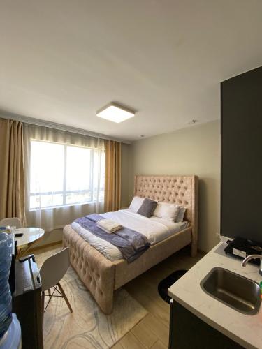 a bedroom with a bed with a window and a sink at Staunch Homes Luxury Studio Apartment in Nairobi