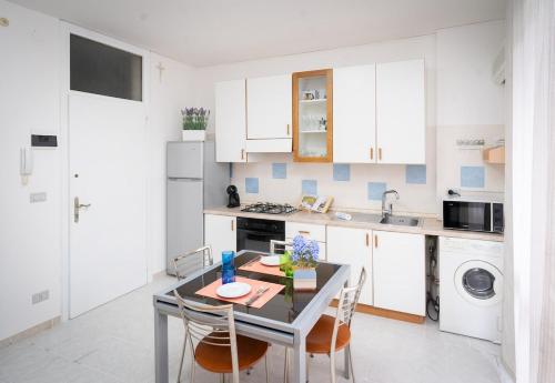 a kitchen with white cabinets and a table with chairs at Dimora del Mare in Isola Bacucco