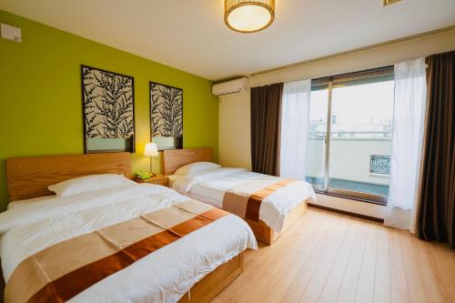 a bedroom with two beds and a large window at 四季歓居-新裝三層一戶建電車直達關西機場難波心斎橋天王寺住吉大社徒歩圏3ldk貸切 in Osaka