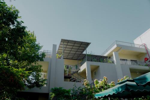 a white building with a balcony and trees in the foreground at Ramat Niwas By Kutani Stays in Jaipur