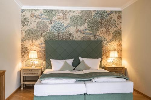 a bedroom with a bed with a green headboard at Hotel Bachmair Alpina in Rottach-Egern