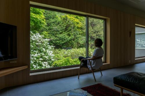 a woman sitting in a chair looking out a window at 左京山SAkyozan in Takayama