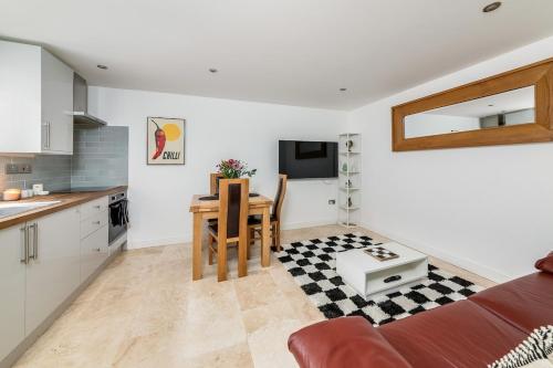 a kitchen and living room with a red couch and a table at Oxford, St Clements, 2-Bed, Minutes to Centre with Private Garden Courtyard in Oxford