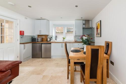 a kitchen with white cabinets and a table and chairs at Oxford, St Clements, 2-Bed, Minutes to Centre with Private Garden Courtyard in Oxford