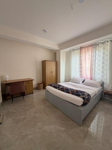 a bedroom with a bed and a desk and a window at Aga Stay Apartment in Gangtok