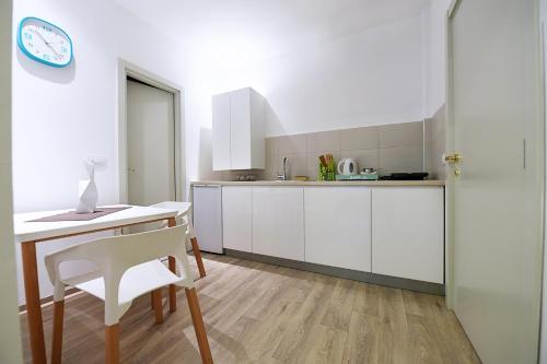 a kitchen with white cabinets and a table and a clock at L9 Top Central Rooms and Apartments 2 in Belgrade