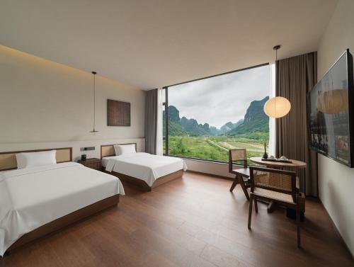 a hotel room with two beds and a large window at Hidden Valley Hotel-- New Hotel,A Hidden Gem,Serene Sanctuary,Exclusive Location,Swimming Pool & Cycling Route,Attraction Tickets Serivce in advance,Affordable Luxury,Best Karst Mount View in Yangshuo in Yangshuo