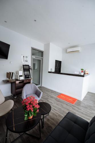 a living room with a couch and a table with flowers at The Marion Hotel Impian Emas Branch in Skudai