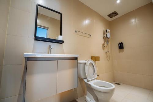 a bathroom with a toilet and a sink and a mirror at The Marion Hotel Impian Emas Branch in Skudai