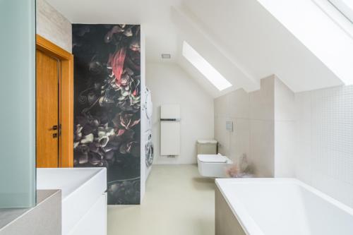a bathroom with a toilet and a wall with a painting at Apartmán VALORI - 100m2 in Poděbrady