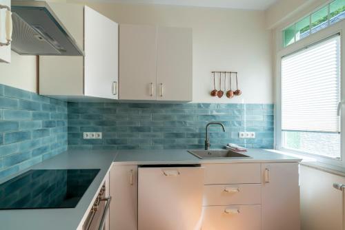 a kitchen with white cabinets and blue tiles at Romantisches Hotel zur Post in Brodenbach