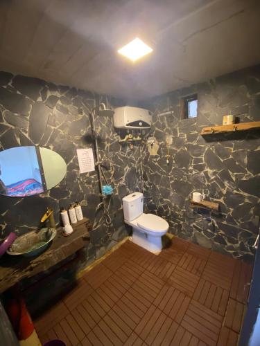 a bathroom with a toilet and a stone wall at Pam Hill in Bản Pha Xum