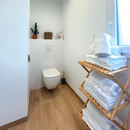 a bathroom with a stack of towels and a toilet at Villa Saint Mart-Tout Inclus-Plage à 7 min à pied in Saint Martin de Brehal