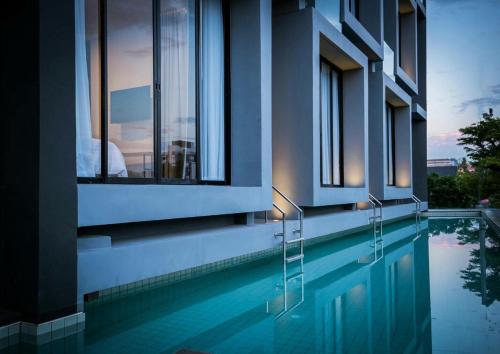 a house with a swimming pool with a view of a building at Kalm Bangsaen Hotel in Bangsaen