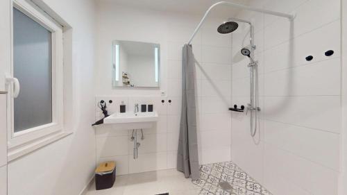 a white bathroom with a shower and a sink at Wohnung mit Heimkino mitten in der Altstadt in Celle