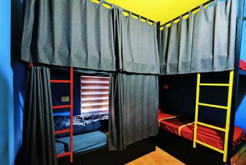 a room with three bunk beds with curtains at Avenue Dorms in Kalpetta