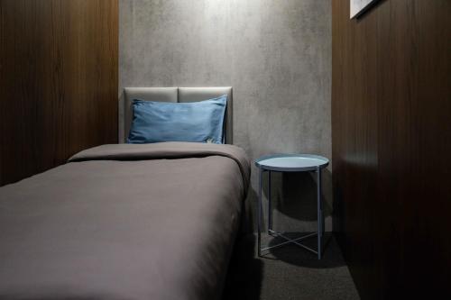 a bed with a blue pillow next to a stool at Sleepover Terminal 1, Concourse D - formerly sleep 'n fly in Dubai