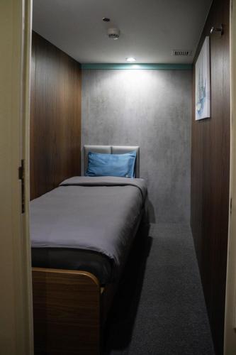 a small bedroom with a bed with a blue pillow at Sleepover Terminal 1, Concourse D - formerly sleep 'n fly in Dubai