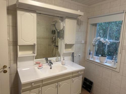 a white bathroom with a sink and a mirror at Privat strandvilla i vackra Geta in Geta