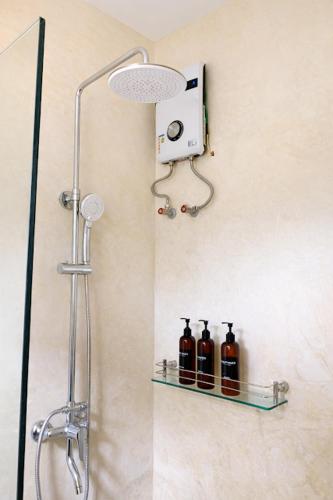 a shower with three bottles on a shelf in a bathroom at Kalija in General Luna