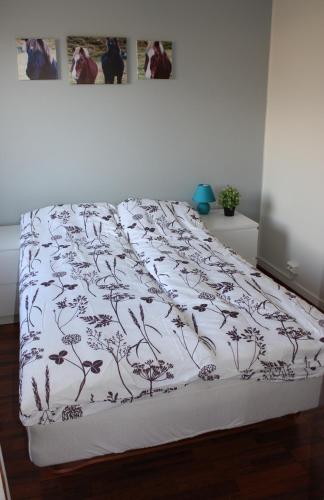 a bed with a white comforter with drawings on it at Skjólsteinar in Grundarfjordur