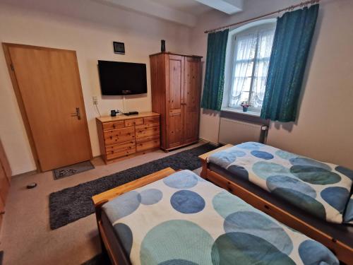 a bedroom with two beds and a flat screen tv at Grenzstübchen in Hötensleben