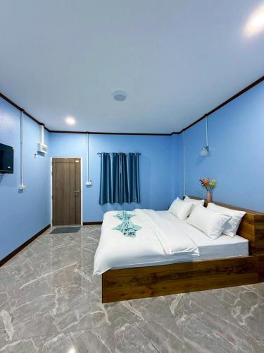 a bedroom with a large bed with a blue wall at Khaosok Bluesky Hotel in Khao Sok National Park