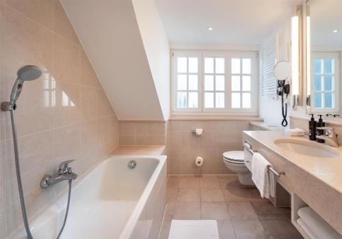 a bathroom with a tub and a toilet and a sink at Dorint Strandresort & Spa Westerland/Sylt in Westerland