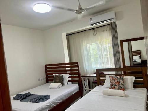 two beds sitting in a room with a window at Leona Homes in Mombasa
