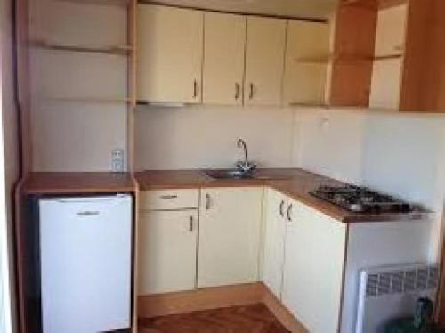 a small kitchen with white cabinets and a sink at ZEcamping 3 pataugeoire animations locatif TV BBQ 24m2 4 pers in La Souterraine