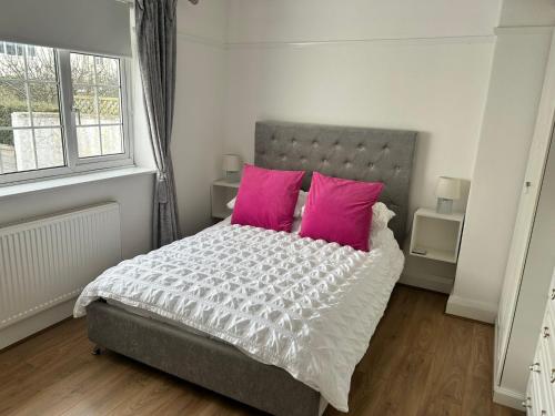 a bedroom with a bed with two pink pillows at 3 bed bungalow Penrhyn Bay Llandudno in Llandrillo-yn-Rhôs