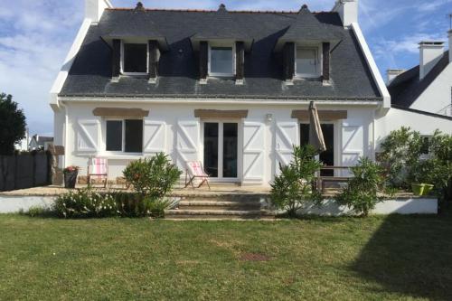 a white house with two chairs in the yard at Grande maison proche plage et centre ville avec grand parking in Quiberon