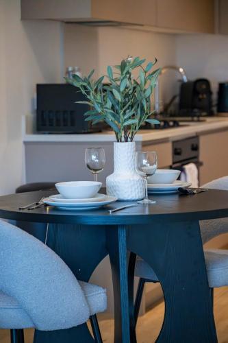 a table with two glasses and a vase with a plant on it at Station Gold Leaf - Gym - Games Room - MK in Milton Keynes